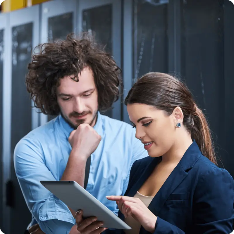 2 people in a server room looking at a tablet