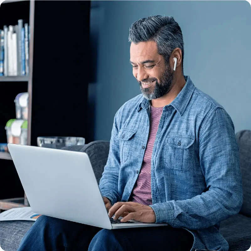 Male worker smiles while looking at laptop in casual setting