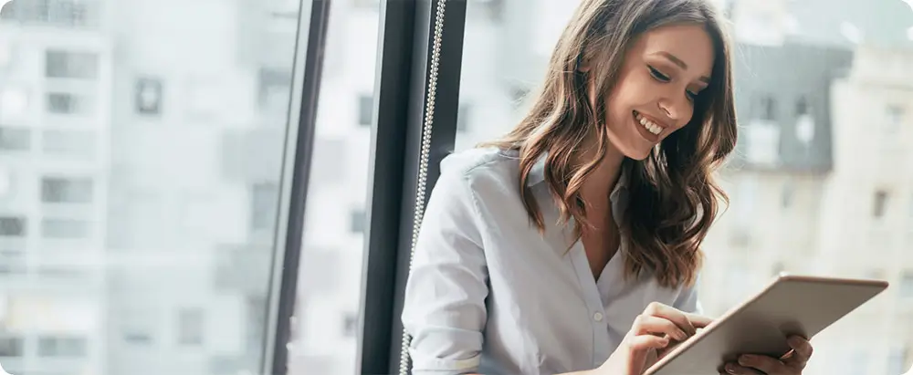 Female business person smiling whilst looking at smart device