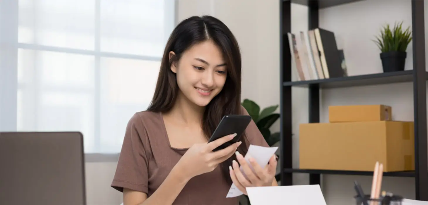 Smiling female checks accounts on mobile device